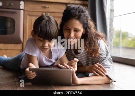 Felice giovane mamma e figlia latino uso tablet Foto Stock