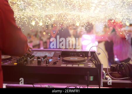 La console di mixaggio è suonata da DJ e coppie che ballano la pista da ballo sullo sfondo e spazio vuoto per testo Foto Stock