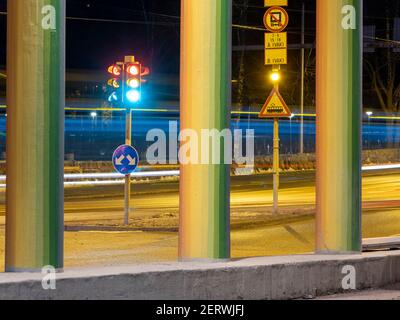 Helsinki / Finlandia - 28 FEBBRAIO 2021: Una vista notturna di un semaforo cittadino dietro le colonne colorate del ponte. Foto Stock