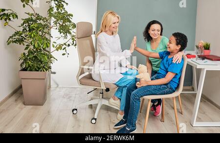 Pediatra amichevole che si diverte con il suo bambino paziente presso l'ufficio del medico. Consultazione, concetto di salute del bambino Foto Stock