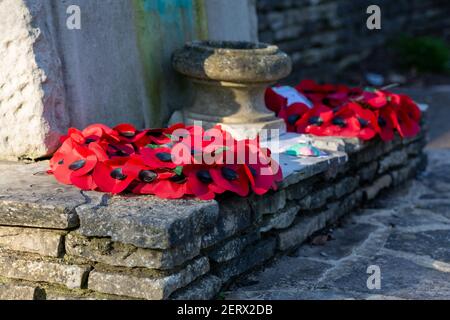 Corone di papavero poste ai piedi su un memoriale di guerra il giorno della memoria Foto Stock