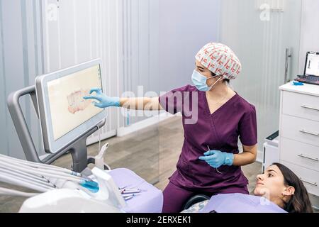 Foto di scorta di una operatrice femminile di una clinica dentale che mostra una radiografia ad un paziente. Foto Stock