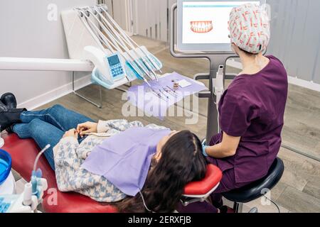Foto di scorta di una operatrice femminile di una clinica dentale che mostra una radiografia ad un paziente. Foto Stock
