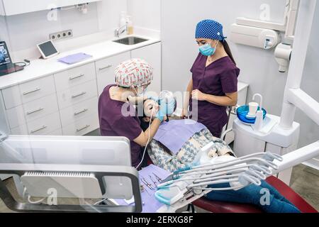 Fotografia di scorta di dentisti femminili non riconosciute che indossano guanti in lattice che esaminano un paziente. Foto Stock