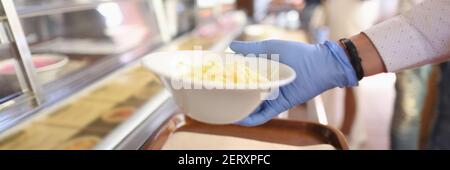 La mano femminile in guanti prende piatto di insalata in caffè Foto Stock