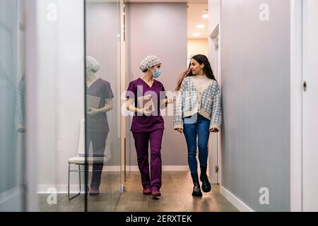 Foto di scorta di dentista femminile che indossa una maschera che parla con il suo giovane paziente nella clinica dentale. Foto Stock