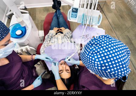 Foto di scorta di dentisti femminili che indossano una maschera protettiva per il viso che esamina un paziente. Foto Stock