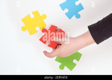 un bambino con autismo raccoglie puzzle, insegnare ai bambini Foto Stock