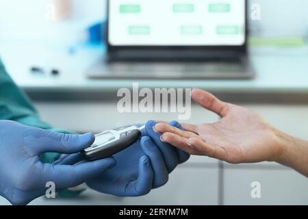 Primo piano lavoratore medico controllo glicemia test per il diabete a. paziente femminile durante l'epidemia di corona Foto Stock