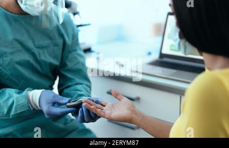 Lavoratore medico controllo glicemia test per il diabete a paziente femminile Durante l'epidemia di virus corona - concetto sanitario Foto Stock