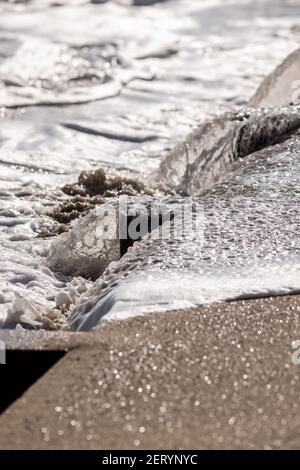 Le onde si infrangono contro il groyne sulla spiaggia di Fisherman’s Walk, Southbourne, Bournemouth, in un giorno di febbraio splendidamente soleggiato durante il COVID-19 coro Foto Stock