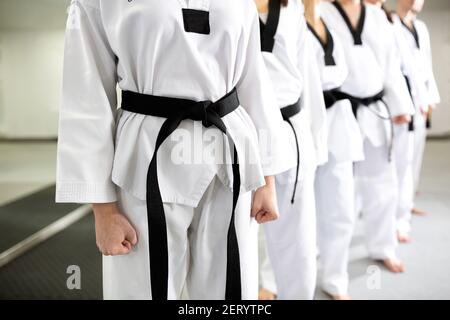 Primo piano di uniformi bianche d'arte marziale che indossano cinture nere, disciplina, devozione, professionalità Foto Stock