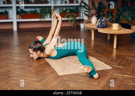 Giovane donna slim che pratica yoga a casa facendo ampio angolo seduta in avanti curva posa. Upavistha konasana. Equilibrio, meditazione, relax e salute l Foto Stock