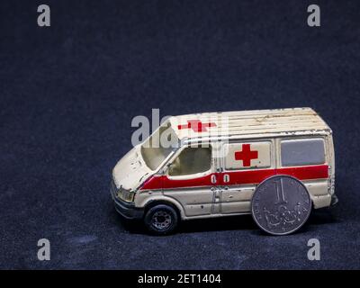 Usti nad Labem / Repubblica Ceca - 11.29.2019: Vecchia auto giocattolo in ambulanza polverosa con moneta appoggiata sul lato - le monete sono la koruna ceca Foto Stock