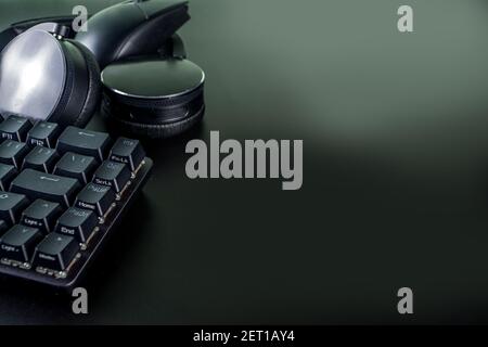 Concetto di dispositivi di gioco e di gioco. Spazio tavolo di lavoro del giocatore sfondo, vista dall'alto. Tastiera, mouse, joystick gamepad, tappetino per mouse e cuffie. Su t nero Foto Stock