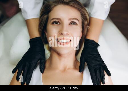 Massaggio viso trattamento di bellezza. Closeup di una giovane donna s viso sdraiato sulla schiena, ottenendo il massaggio di sollevamento del viso, pizzicare e rotolare tecnica Foto Stock