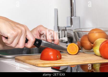 Donna con le mani in mano il taglio di pomodoro, dietro di verdure fresche. Foto Stock