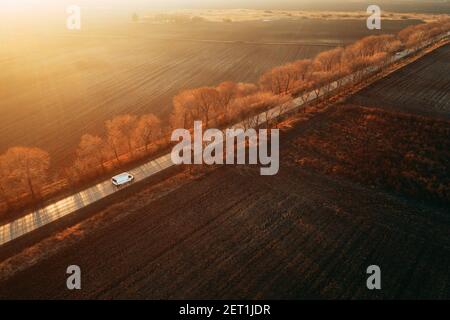 Vista aerea del minivan sulla strada al tramonto, drone pov alto angelo vista Foto Stock