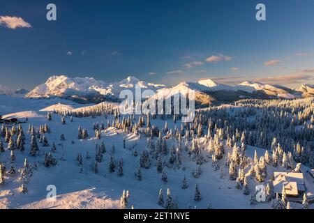 Vista aerea del paesaggio invernale con foresta innevata in montagna con bella luce del tramonto. Foto Stock