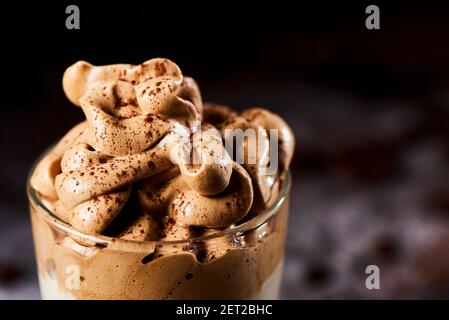 primo piano di un delizioso caffè dalgona servito in un bicchiere, su sfondo grigio scuro Foto Stock