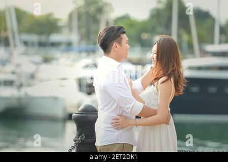 Ritratto di una coppia innamorata in piedi presso un porto turistico, Singapore Foto Stock