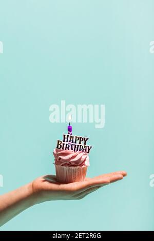 La mano della donna tiene il cupcake di compleanno con la candela. Buon compleanno. Celebrazione. Foto Stock