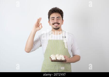 Ritratto di cuoco maschio sorridente che tiene funghi crudi su bianco sfondo Foto Stock