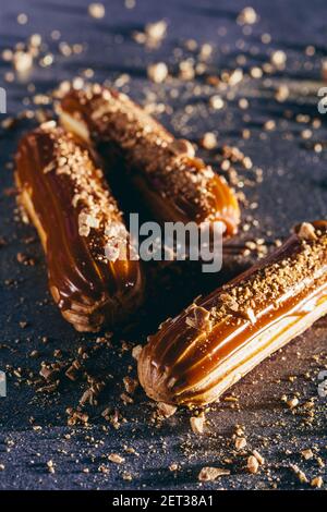 Eclair per tofee cosparsi di scintille su bancone scuro. Pasticceria francese tradizionale. Primo piano. Foto Stock