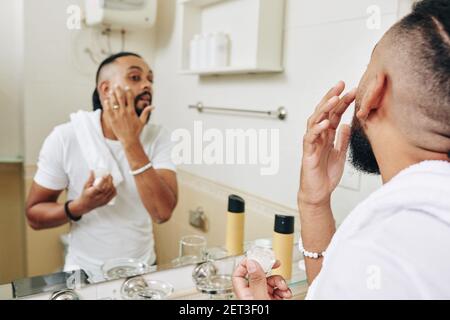 Uomo che applica lozione idratante Foto Stock