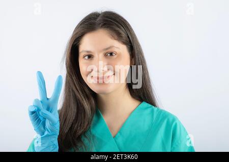 Ritratto di una giovane dottoressa in uniforme verde che mostra segno della vittoria Foto Stock