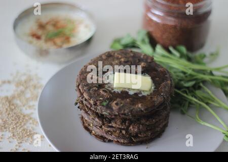 Pane piatto con finger millet e foglie di fenugreek servito con cagliata di masala. Si chiama anche Nachni methi thepla, un pane piatto sano e gustoso da Foto Stock