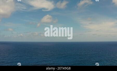 Oceano blu con onde e cielo con nuvole, vista dall'alto del mare. Sfondo orizzonte nuvola d'acqua. Acqua di mare blu con onde contro il cielo. Foto Stock