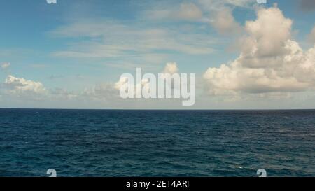 Oceano blu con onde e cieli blu con nuvole. Panorama delle acque blu e del cielo, vista dall'alto. Sfondo orizzonte nuvola d'acqua. Foto Stock