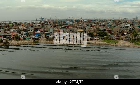 Zona delle baraccopoli vicino al porto di Manila, Phillippines, vista dall'alto. Molta immondizia in acqua. Foto Stock