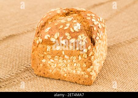 Pane integrale con avena sullo sfondo del burlap. Foto Stock