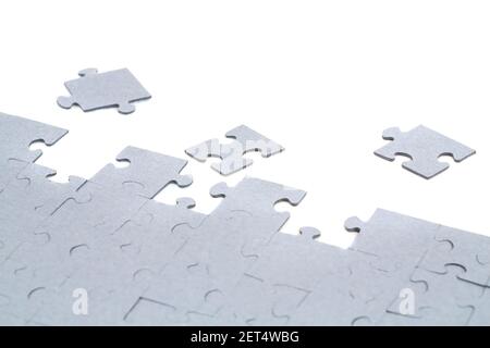 Pezzi di puzzle incompleti su sfondo bianco. Foto Stock