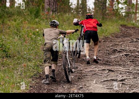 indietro due alpinisti maschili camminano in salita sul sentiero forestale Foto Stock