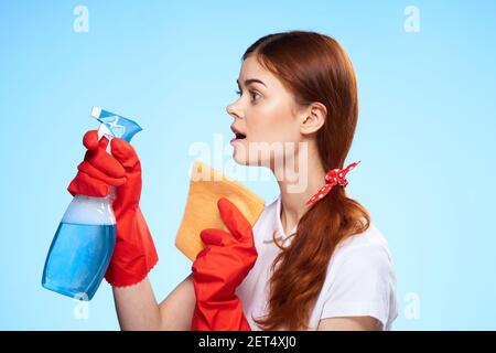 donna con prodotti per la pulizia nelle mani di un servizio professionale consegna sfondo blu Foto Stock