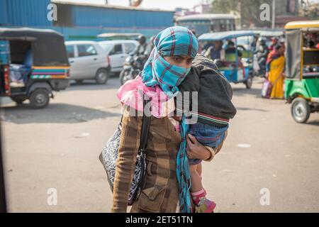 Jaipur, India. 09-05-2018. Madre che porta suo figlio mentre cammina alla frutta e verdura locale nel mercato di Jaipur. Foto Stock