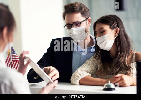 Coppia adulta che indossa maschere per il check-in in hotel Foto Stock