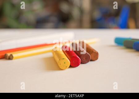 Un primo piano di materiali d'arte, tra cui i colorati pastelli ad olio e matite colorate su una superficie di tavolo grunge Foto Stock