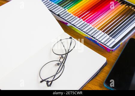 Scrivania dell'artista con articoli da disegno professionali, bicchieri circolari e telefono Foto Stock