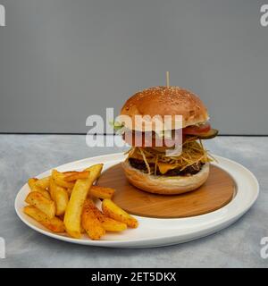 Hamburger e patatine fritte pronti su sfondo grigio e. sottopiano blu Foto Stock