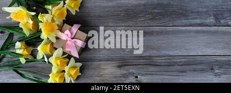 Vista dall'alto di una confezione regalo con narcisi gialle Tavole di legno intemperie per il concetto di vacanza amore di giorno delle madri Foto Stock