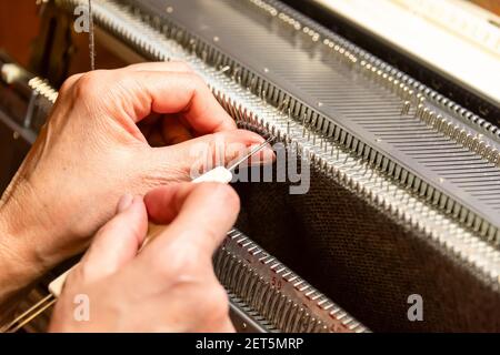 Mani donne che lavorano con la macchina per maglieria, lavorare a maglia come hobby donne. Piccola impresa di produzione di indumenti, moda lenta Foto Stock