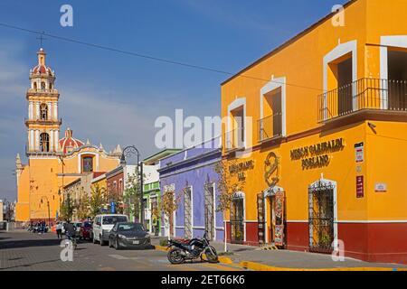 Strada colorata con ristoranti e chiesa parrocchiale per il comune di San Pedro lungo la Plaza de la Concordia / Zócalo a Cholula, Puebla, Messico Foto Stock