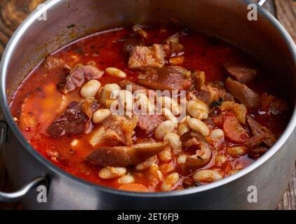 Una pentola grande con fagioli e stufato di coscia di maiale affumicato su  una tavola di legno Foto stock - Alamy