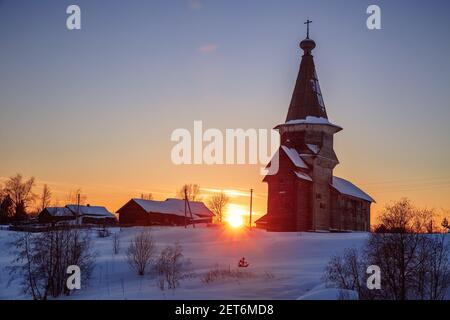 Paesaggio invernale rurale tramonto. La vecchia chiesa russa in legno di Elia il Profeta nel villaggio di Saminsky Pogost, regione di Vologda, Russia Foto Stock