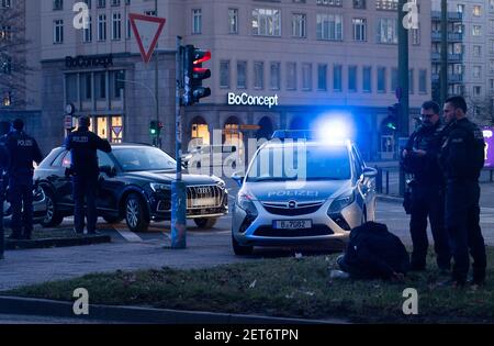 Berlino, Germania. 01 Marzo 2021. Durante un'operazione di polizia a Strausberger Platz, un uomo manettato si siede sulla punta dell'erba mentre un'automobile è parcheggiata nel traffico in arrivo. Credit: Christophe Gateau/dpa - ATTENZIONE: (Le targhe sono state pixelate per motivi di privacy)/dpa/Alamy Live News Foto Stock