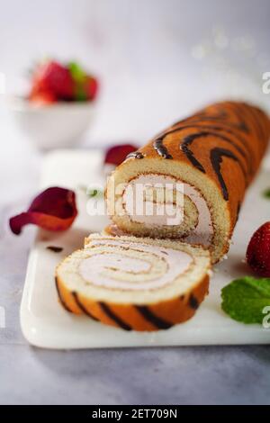 Strawberry Swiss roll o roulade con ripieno di crema e gocce di cioccolato, fuoco selettivo Foto Stock
